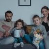 A family cuddled up together on the couch watching a kids' movie on Netflix
