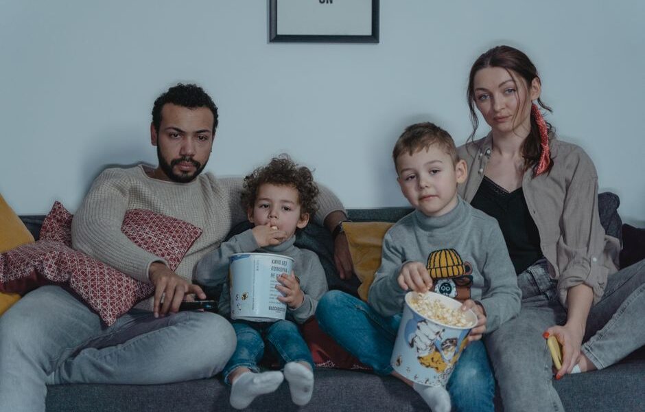 A family cuddled up together on the couch watching a kids' movie on Netflix