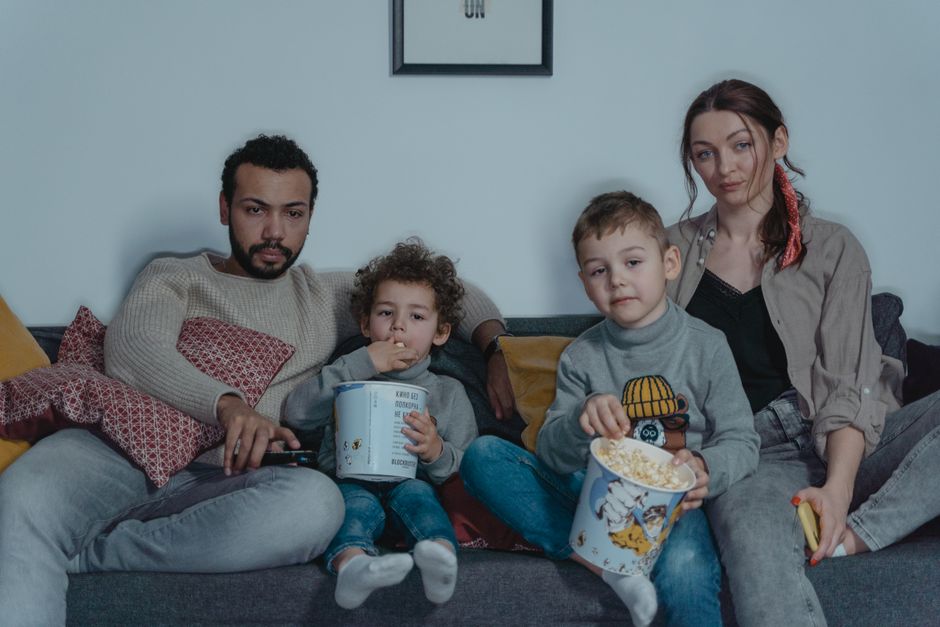 A family cuddled up together on the couch watching a kids' movie on Netflix