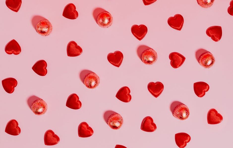 Collection of affordable Valentine's Day gifts under $50 including candles, jewelry, and a photo book arranged on a table