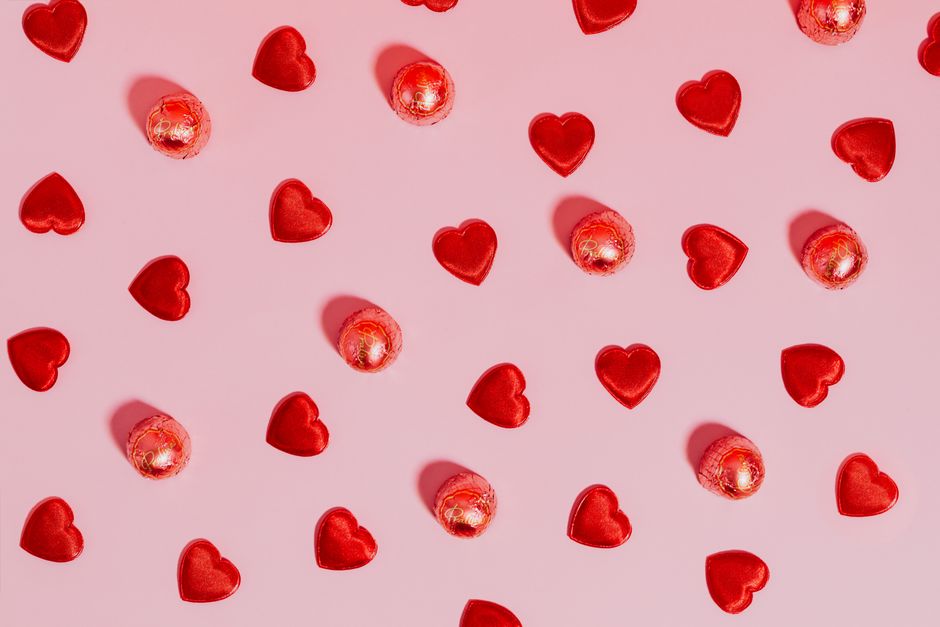 Collection of affordable Valentine's Day gifts under $50 including candles, jewelry, and a photo book arranged on a table
