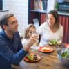 Family of four eating a cheap homemade dinner together at the kitchen table