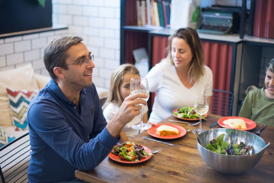 Family of four eating a cheap homemade dinner together at the kitchen table