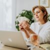 Person calculating daily side hustle earnings on a laptop with cash nearby