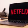 Person holding a remote control while browsing Netflix shows on a TV screen