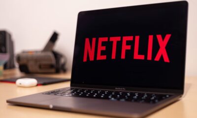 Person holding a remote control while browsing Netflix shows on a TV screen