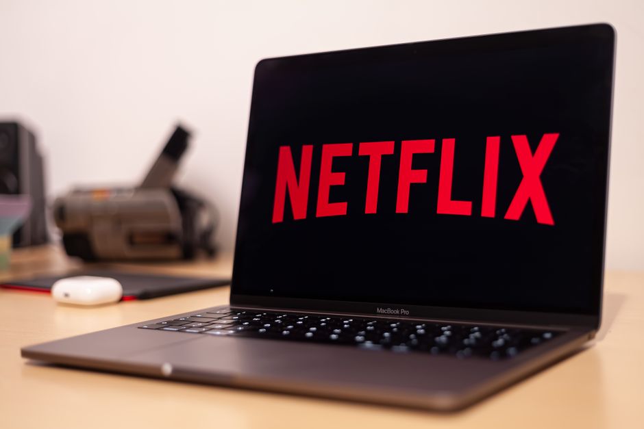 Person holding a remote control while browsing Netflix shows on a TV screen