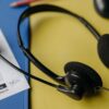 Person listening to top charting songs on headphones with a smartphone showing a music streaming app
