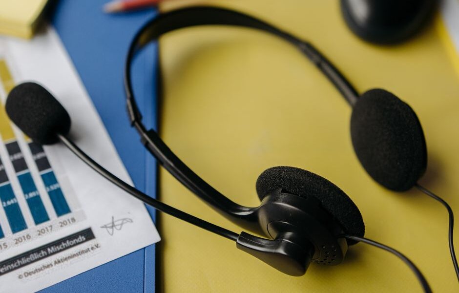 Person listening to top charting songs on headphones with a smartphone showing a music streaming app