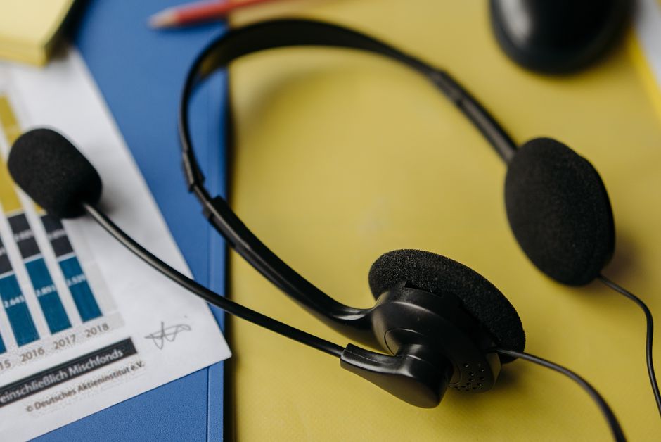 Person listening to top charting songs on headphones with a smartphone showing a music streaming app