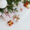 Stack of wrapped Christmas gifts in various sizes under a decorated tree