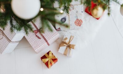 Stack of wrapped Christmas gifts in various sizes under a decorated tree
