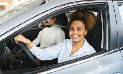 Driver reviewing auto insurance policy documents with a car in the background in New York