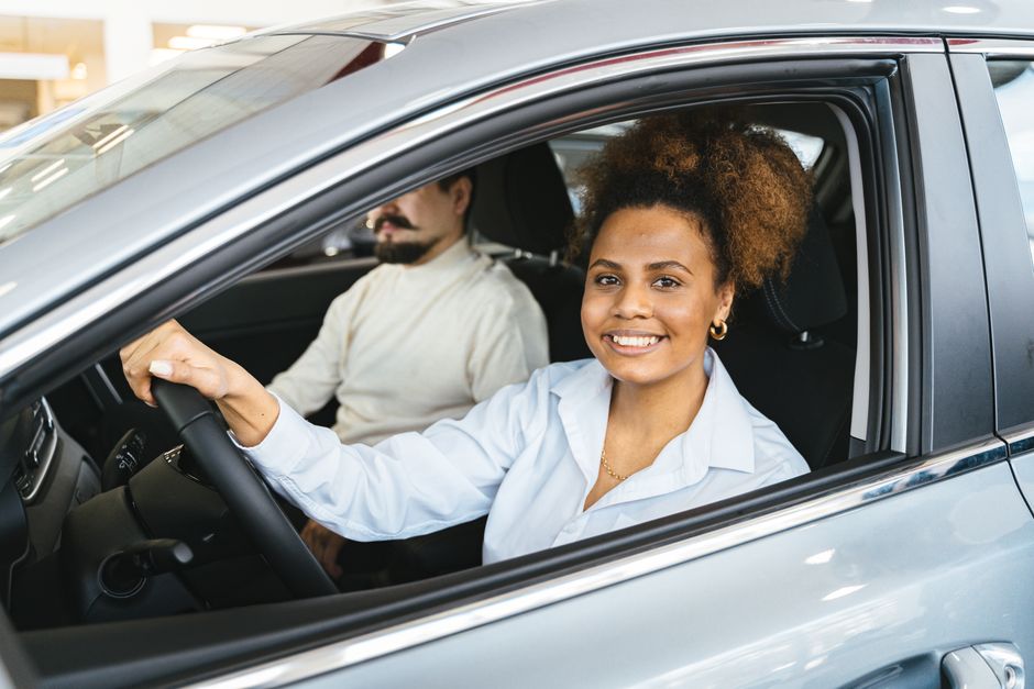 Driver reviewing auto insurance policy documents with a car in the background in New York