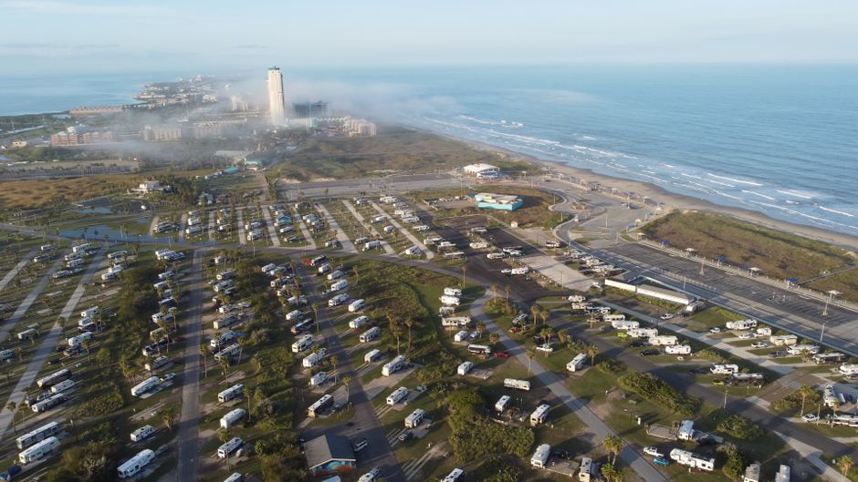 Rows of RVs and travel trailers parked at an RV dealership lot in Texas